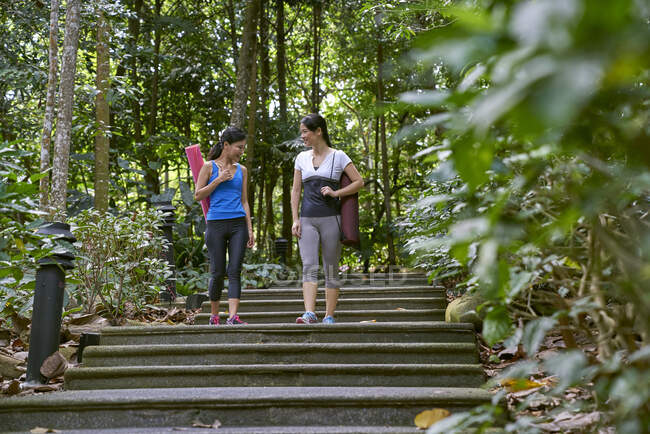 Zwei Frauen auf dem Weg zu ihrem Yoga-Standort im Botanischen Garten in Singapur — Stockfoto