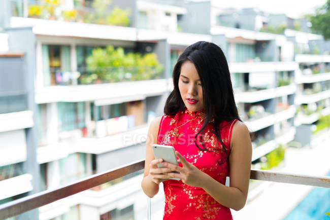 Feliz mulher asiática usando smartphone na varanda — Fotografia de Stock
