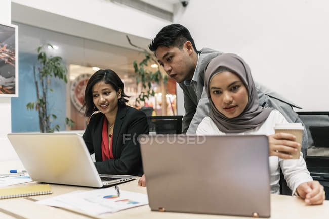 Junge multikulturelle Geschäftsleute, die mit digitalen Geräten im modernen Büro arbeiten — Stockfoto