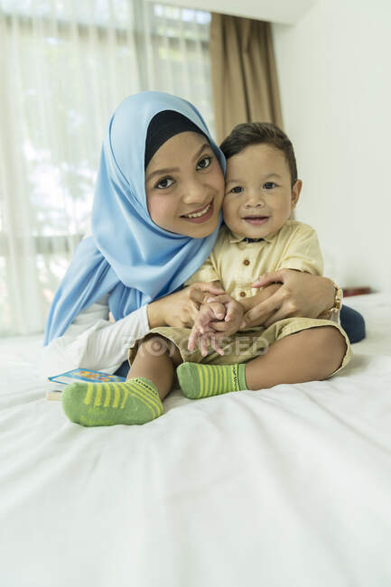 Madre e hijo sonriendo a la cámara interior - foto de stock