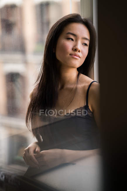 Retrato de mulher chinesa bonita dentro de casa ao lado de uma janela com luz natural — Fotografia de Stock