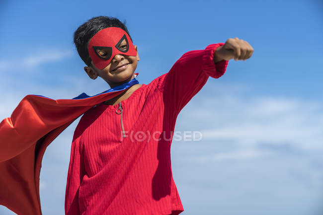 Superhéroe niño contra el fondo del cielo azul - foto de stock