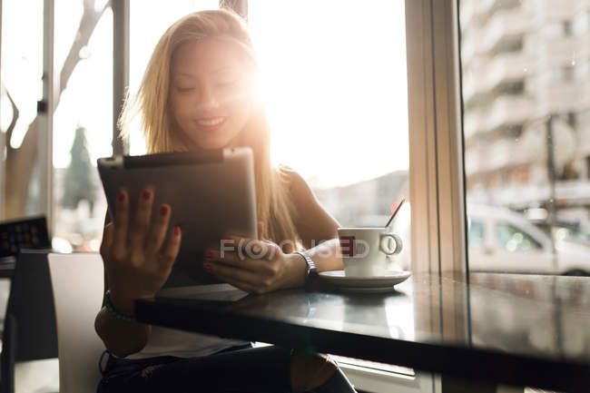 Porträt einer schönen jungen Frau, die ihr digitales Tablet im Café benutzt. — Stockfoto