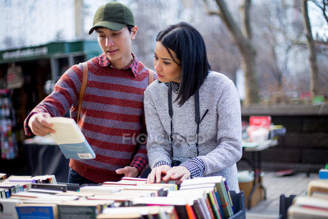 Turistas pareja mirando libros en el mercado callejero - foto de stock