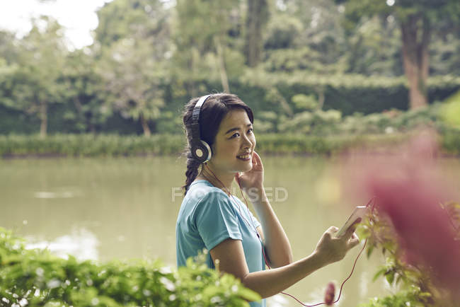 Портрет женщины, слушающей музыку во время прогулки по Ботаническому саду — стоковое фото