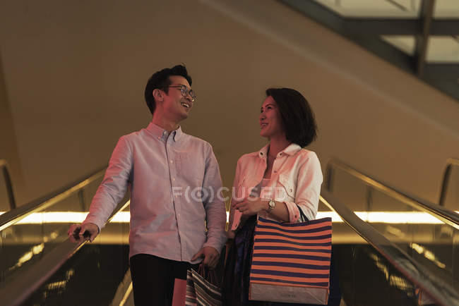 Jeune casual asiatique couple avec sacs à shopping dans le centre commercial — Photo de stock