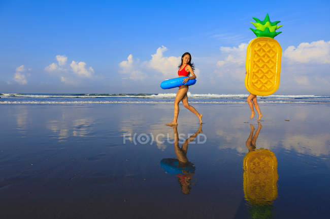 Дві красиві дівчата з повенями на шляху до хвиль океану . — стокове фото