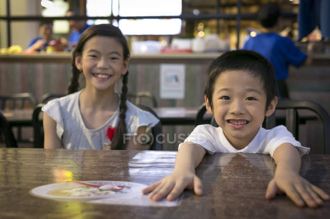 Dos feliz joven asiático niños mirando cámara en café - foto de stock