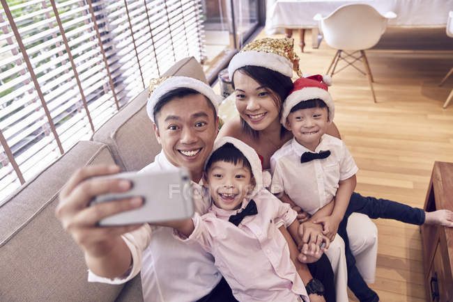 Feliz asiático familia celebrando navidad juntos y tomando selfie - foto de stock