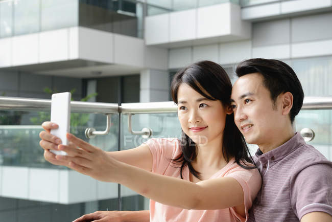 Mature asian casual couple taking selfie on smartphone — Stock Photo