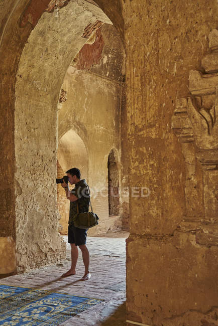 Молодой человек делает фотографию внутри древнего храма, Пагода, Баган, Мьянма — стоковое фото