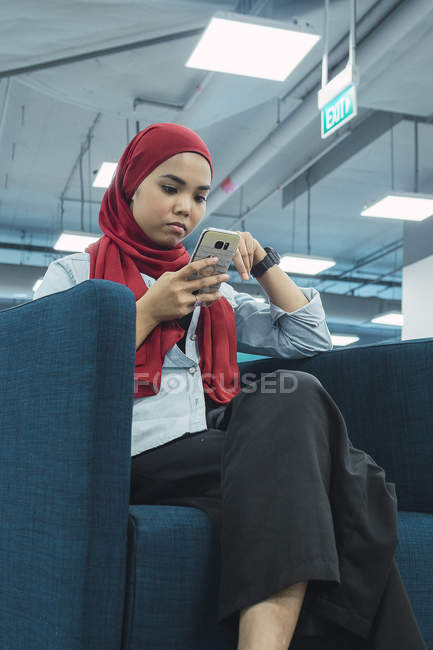 Молода азіатська бізнес-леді використовує смартфон в сучасному офісі — стокове фото