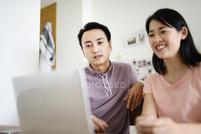 Mature asian casual couple using laptop together at home — Stock Photo