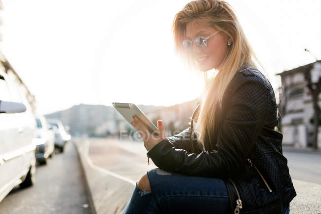 Portrait de belle jeune femme utilisant sa tablette numérique dans la rue . — Photo de stock