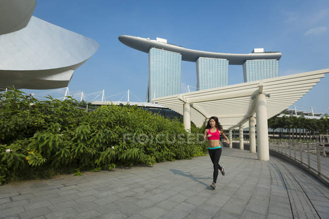 Uma jovem mulher asiática está correndo na área da baía marina de Cingapura . — Fotografia de Stock