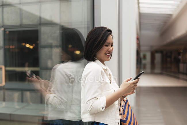 Joven casual asiático mujer usando inteligente en centro comercial - foto de stock