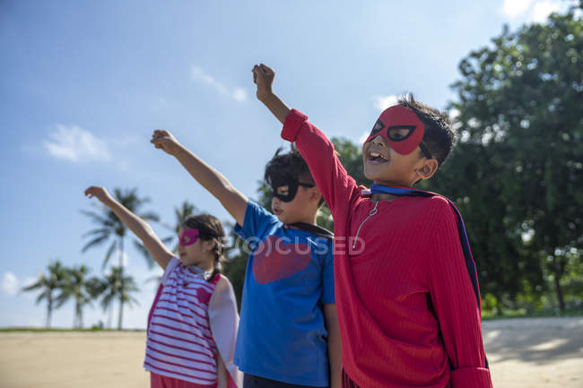 Retrato de niños superhéroes con las manos levantadas - foto de stock