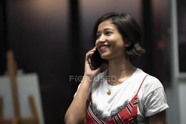 Молода азіатська бізнес-леді зі смартфоном в сучасному офісі — стокове фото