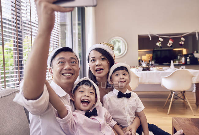 Happy young asian family celebrating christmas together and taking selfie — Stock Photo