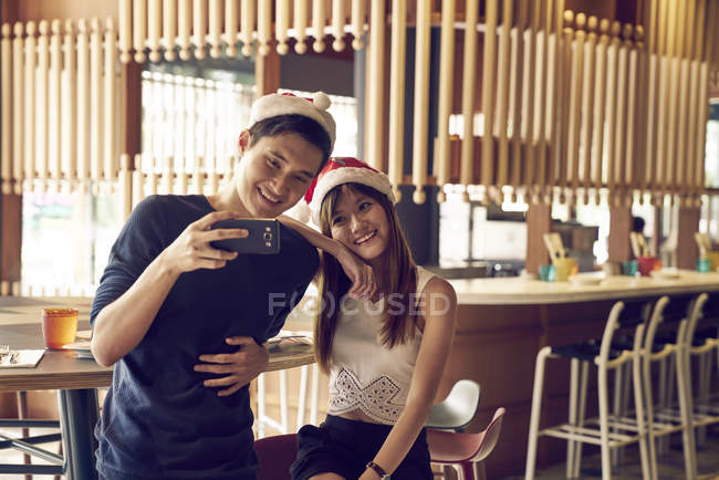 Pareja de jóvenes asiáticos amigos juntos tomando selfie en Navidad - foto de stock