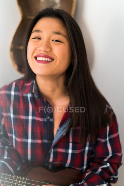 Young attractive asian woman playing on ukulele — Stock Photo