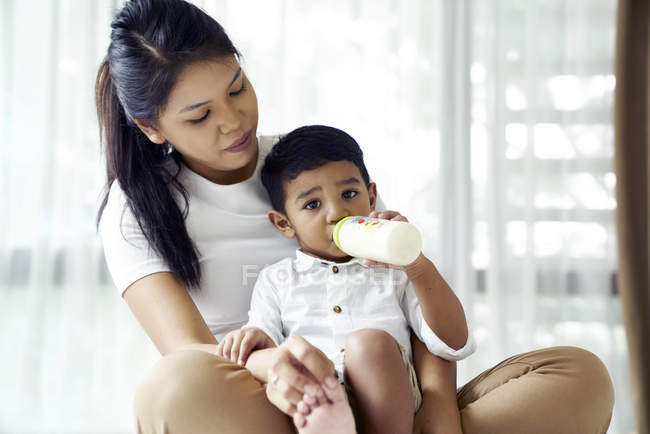 Mãe observa como seu filho se alimenta de garrafa de leite — Fotografia de Stock