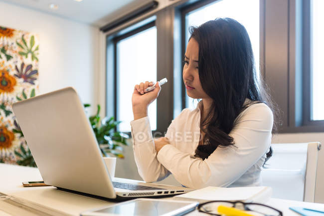 Молода жінка працює на ноутбуці в сучасному офісі — стокове фото