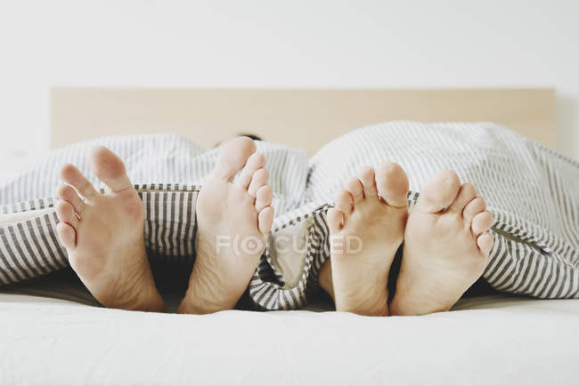 Imagem cortada de casal deitado na cama, apenas pés — Fotografia de Stock