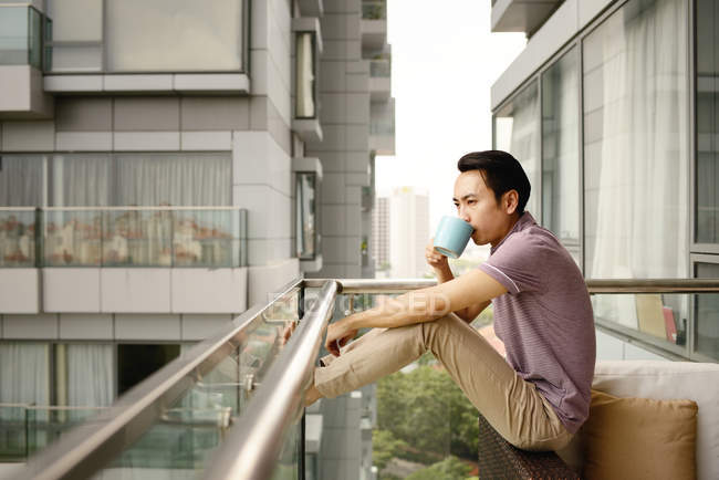 Reifen asiatische casual Mann trinken Kaffee auf Balkon — Stockfoto