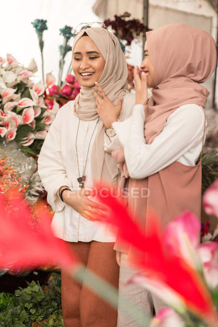 Дві молоді мусульманські дівчата в квітковому магазині весело розмовляють — стокове фото