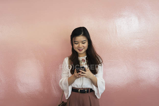 Молодая случайная азиатская девушка с помощью смартфона — стоковое фото