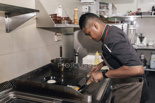 Young asian chef cooking at restaurant kitchen — Stock Photo