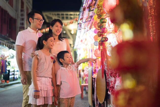 Familia joven caminando por la ciudad mirando a la hermosa decoración de año nuevo chino. - foto de stock
