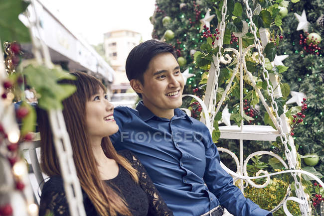 Пара молодих азіатських друзів разом сидить біля ялинки — стокове фото