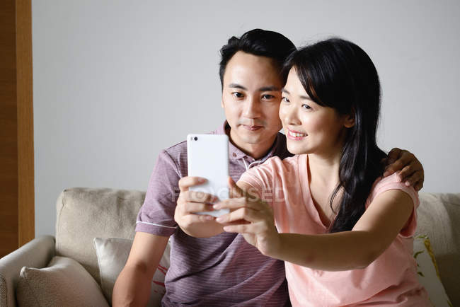 Mature asian casual couple taking selfie on smartphone — Stock Photo