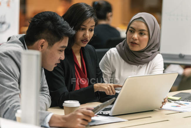Jovens empresários multiculturais que trabalham com dispositivos digitais em escritórios modernos — Fotografia de Stock