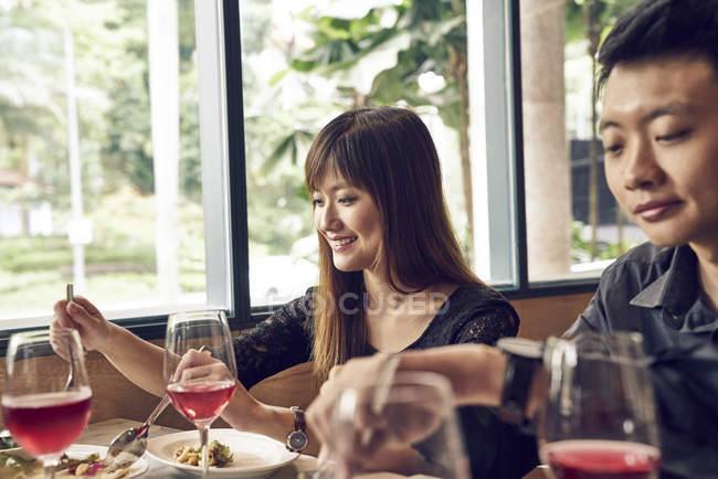 Company of young asian friends together eating in cafe — Stock Photo