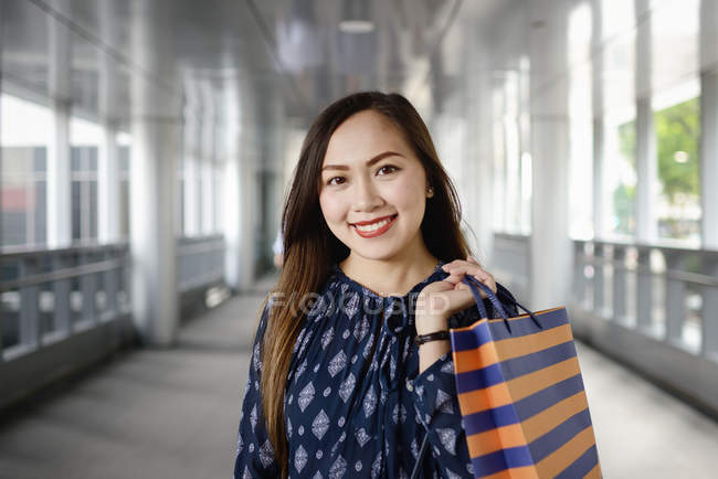 Feliz hermosa mujer asiática en compras con bolsa de compras - foto de stock