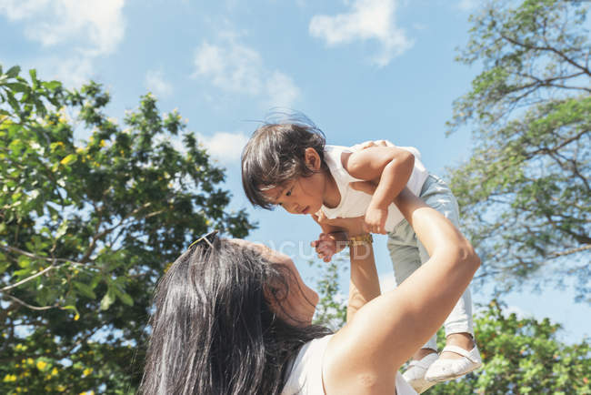 Young mother holding asian daughter in hands — Stock Photo