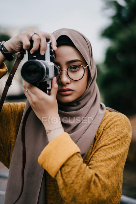 Jovem asiático muçulmano mulher no hijab tomando foto com câmera — Fotografia de Stock