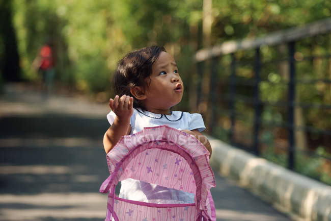 Little girl walking in park with baby carriage — Stock Photo