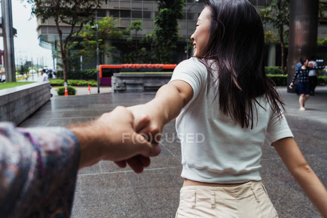 Молодий привабливою азіатські жінки, тримаючись за руки з людиною — стокове фото