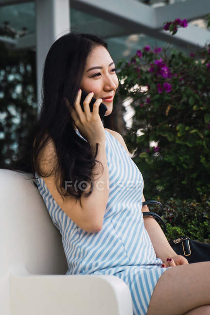 Jeune femme asiatique en utilisant smartphone sur canapé — Photo de stock