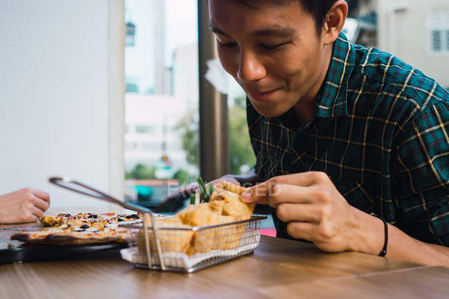 Joven asiático hombre comer en cómodo bar - foto de stock