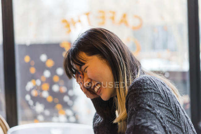 Young attractive casual asian woman laughing in cafe — Stock Photo