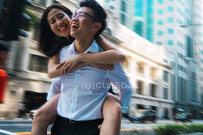 Young adult business couple, man giving piggyback ride — Stock Photo