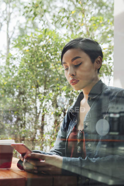 Porträt einer jungen malaysischen Singaporeanerin, die sich bei einer Tasse Kaffee amüsiert. — Stockfoto