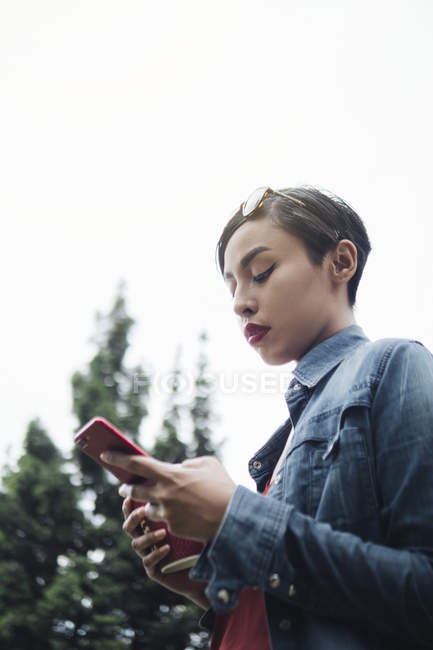 Portraits of a young Singaporean Malay lady using her phone in an urban setting on the streets of Singapore. — Stock Photo