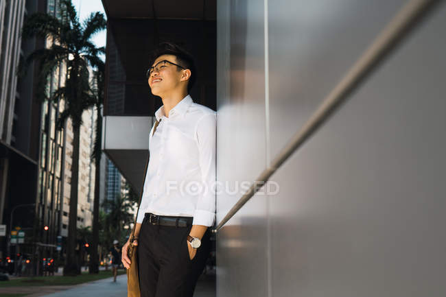 Bem sucedido jovem empresário em pé por parede — Fotografia de Stock