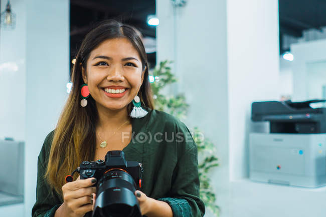 Young asian business woman with camera in modern office — Stock Photo